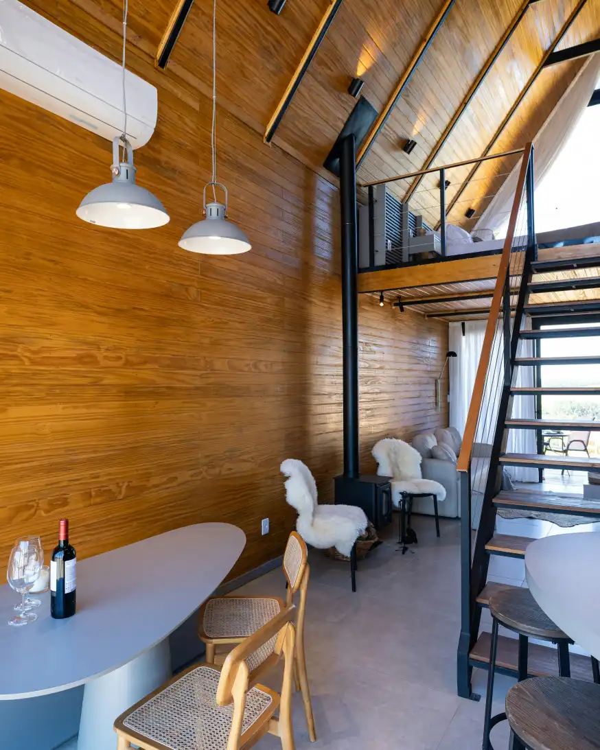 Loft Ban Công ốp gỗ: gác lửng phía trên, cầu thang dốc, bàn tròn và ghế lót lông cừu bên dưới