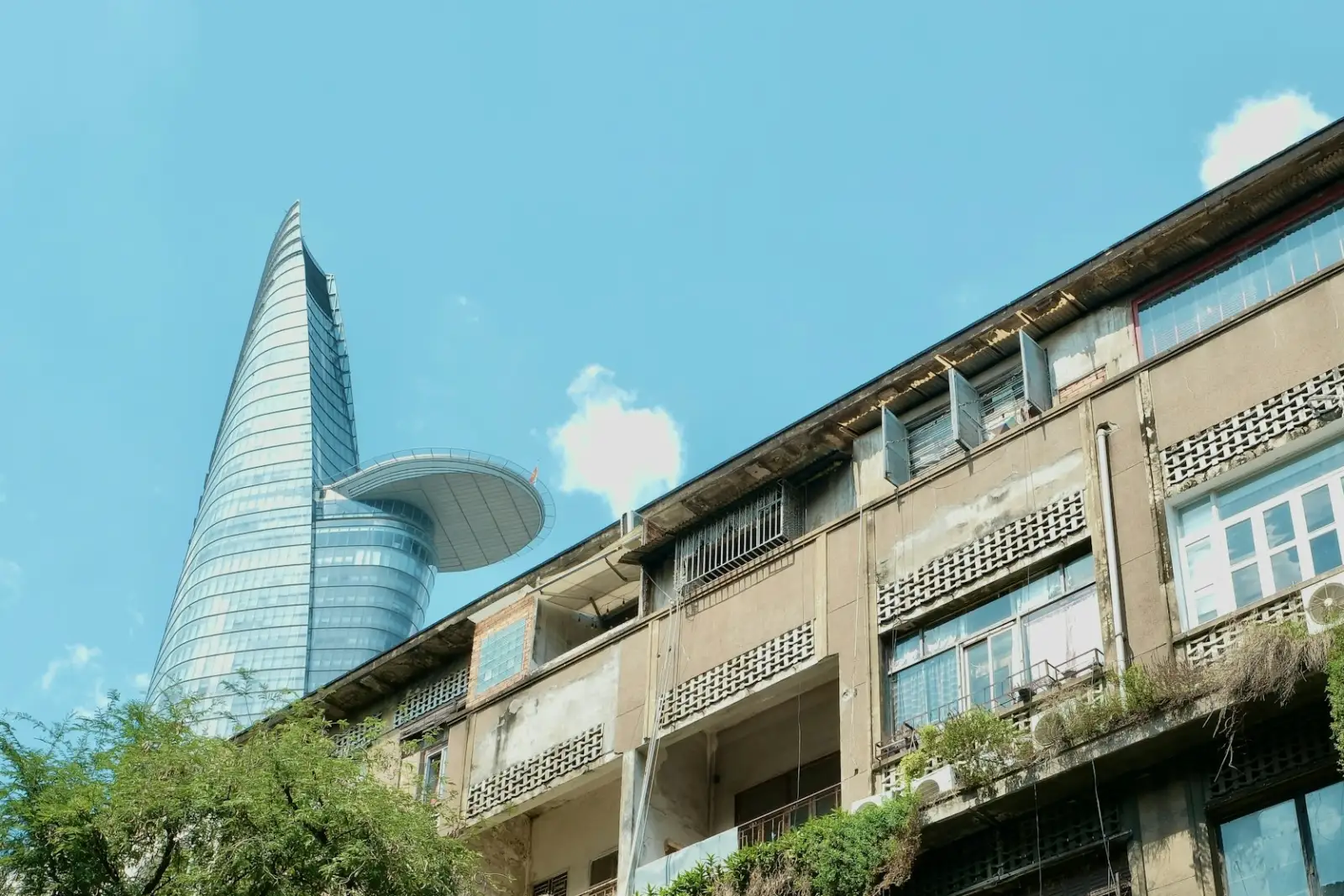 Mặt tiền một tòa nhà cũ ở trung tâm Sài Gòn với tường gạch thông gió và cây leo, phía sau là tháp Bitexco (Ảnh minh họa – không phải ảnh tư liệu của công trình)